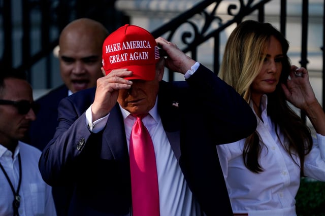 President Donald Trump puts on a "Make America Great Again" hat on the South Lawn of the White House in Washington, DC, on Friday, July 4.