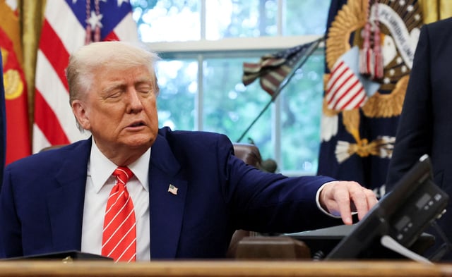 U.S. President Donald Trump reaches for his phone as he makes an announcement about a trade deal with the U.K., in the Oval Office at the White House in Washington, D.C., U.S., May 8, 2025. REUTERS/Leah Millis/File Photo