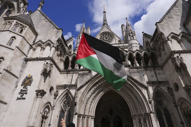 A demonstrator waves a flag outside the High Court in London where a full hearing on an application for a judicial review by Palestine Action against its impending proscription is being heard, Monday, July 21, 2025. (AP Photo/Kirsty Wigglesworth)