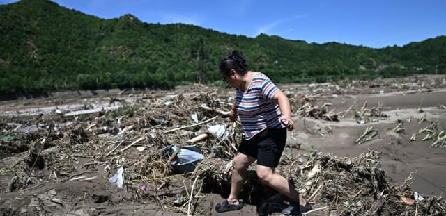 Une femme passe devant une zone endommagée par les pluies dans le district de Huairou, à la périphérie de Pékin, le 30 juillet 2025