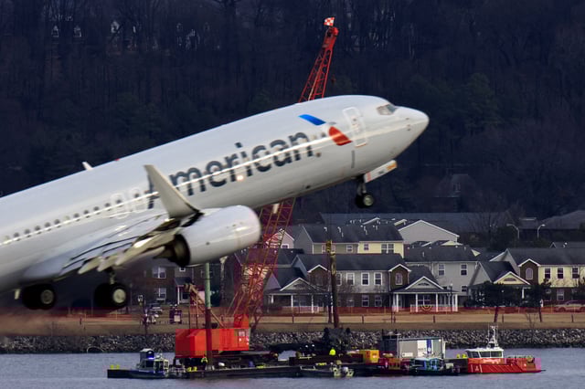A crane retrieves part of the helicopter from the Potomac River as an American plane departs, in the aftermath of the collision of American Eagle flight 5342 and a Black Hawk helicopter that crashed into the river, by the Ronald Reagan Washington National Airport, in Arlington, Virginia, U.S., February 6, 2025. REUTERS/Eduardo Munoz/File Photo