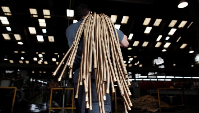 An employee carries copper hoses at the Sociedade Paulista de Tubos Flexiveis metallurgical company which manufactures flexible metal hoses, in Sao Paulo April 20, 2012.