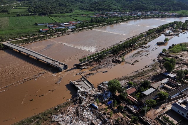 A drone view shows damaged roads and fallen trees next to the overflowing Qingshui river after heavy rainfall flooded the area, in Miyun district of Beijing, China July 29, 2025. REUTERS/Florence Lo/File Photo