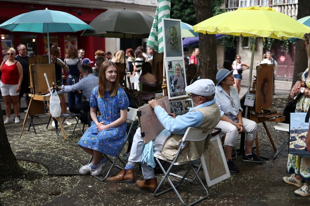 An artists creates a portrait of a tourist on the street in Montmartre, Paris, France, July 29, 2025. REUTERS/Tom Nicholson/File Photo