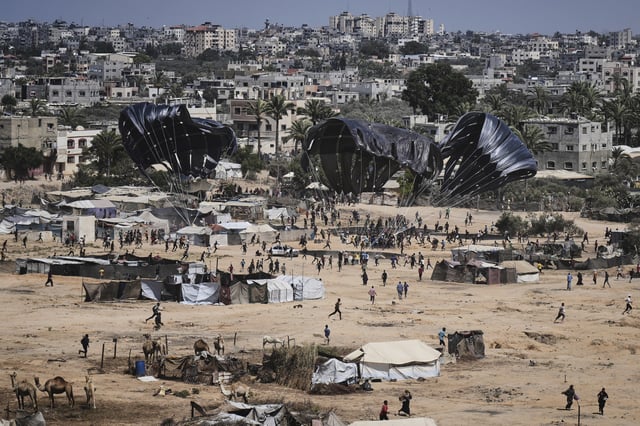 Palestinians rush to collect humanitarian aid airdropped into Zawaida in central Gaza Strip, Thursday, July 31, 2025. (AP Photo/Abdel Kareem Hana)