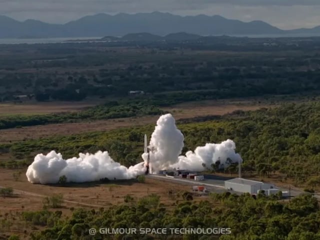 An aerial photo of a rocket taking off from a landing pad surrounded by smoke