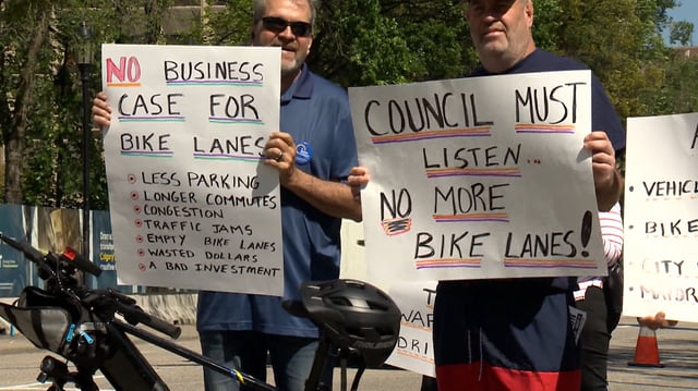 A group of protestors gather Wednesday outside a closed door meeting between the Mayor of Calgary and the Alberta Transportation Minister where the future of bike lanes in the city was one of the main topics of discussion.