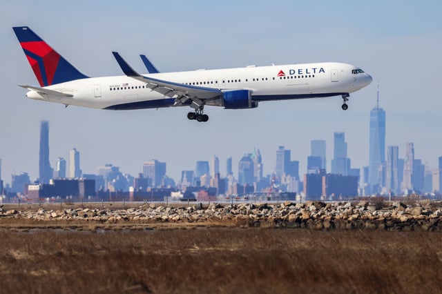 A Delta flight arrives at JFK International Airport in New York as the Manhattan skyline looms in the background on February 7, 2024.