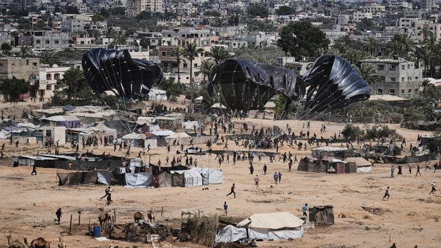 Palestinians rush to collect humanitarian aid airdropped into Zawaida in the central Gaza Strip on Thursday. Foreign Affairs Minister Anita Anand said Jordan facilitated the airdrop.