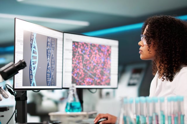 A medical doctor using advanced DNA technology, looking at computer screens.