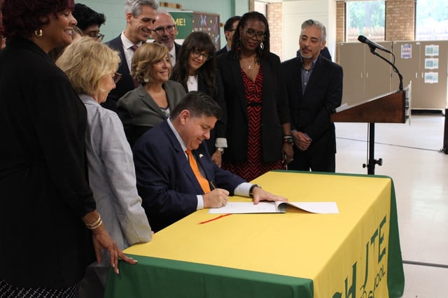 Governor JB Pritzker, at Chute Middle School in Evanston on July 31, 2025, signs into law a mandate that will require Illinois public schools to offer students between 3rd and 12th grades an optional mental health screening. (Richard Requena/Pioneer Press)