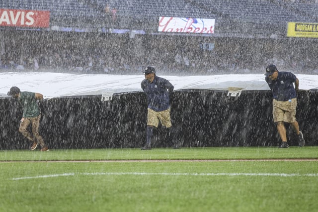 The Grounds crew roll out the tarp during a rain delay in the fifth inning of a baseball game between the New York Yankees and the Tampa Bay Rays, Thursday, July 31, 2025, in New York. (AP Photo/Heather Khalifa)