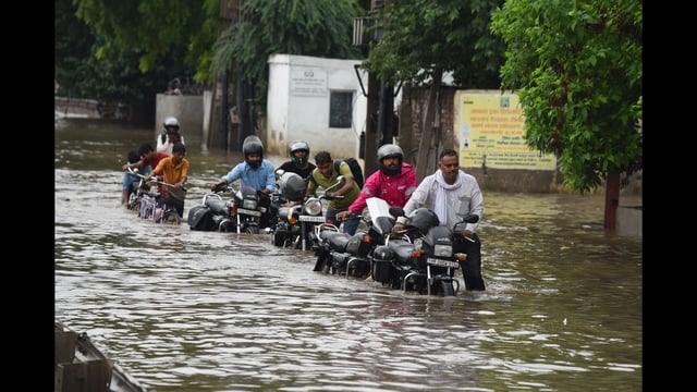 Commuters wade through a waterlogged stretch on NH-48 service road near Narsinghpur village in Gurugram on Thursday. (PARVEEN KUMAR)