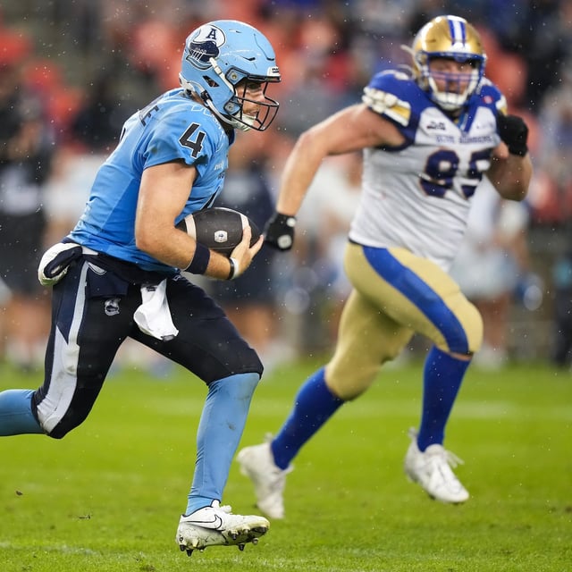 Toronto Argonauts quarterback Nick Arbuckle (4) runs the ball past Winnipeg Blue Bombers defensive lineman Jake Thomas (95) during first half CFL football action in Toronto on Saturday, July 26, 2025. THE CANADIAN PRESS/Nathan Denette