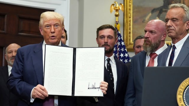 President Donald Trump holds up a signed executive order restarting the Presidential Fitness Test in public schools as Commerce Secretary Howard Lutnick, from left, professional golfer Bryson DeChambeau, WWE CCO Triple H and Health and Human Services Secretary Robert F. Kennedy Jr. watch.