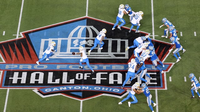 Jul 31, 2025; Canton, Ohio, USA; Los Angeles Chargers quarterback Trey Lance (5) hands off to running back Hassan Haskins (28) in the third quarter against the Detroit Lions at Tom Benson Hall of Fame Stadium. Mandatory Credit: Scott Galvin-Imagn Images