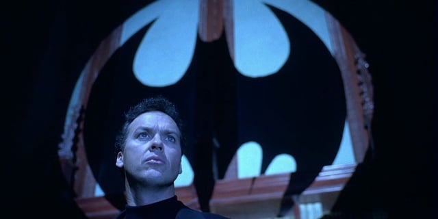Michael Keaton as Bruce Wayne standing in front of the Bat signal in Batman Returns
