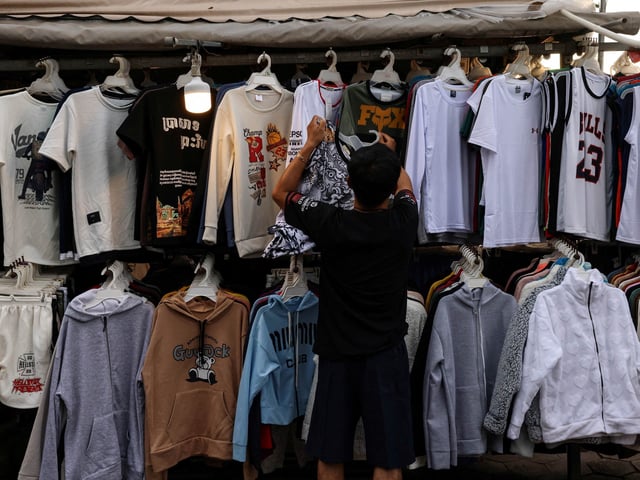 A vendor hangs clothes at a stall at a night market in Phnom Penh, Cambodia, August 1, 2025. REUTERS/Tyrone Siu