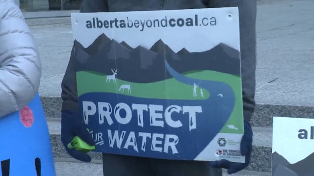 A protestor holds a sign outside the offices of the Alberta Energy Regulator in January 2025, where a hearing on Northback Holdings application to explore for coal in the Grassy Mountain area was being held. The AER ultimately approved the company's exploration plans.