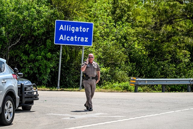 A Florida Highway Patrol officer looks on as protesters gather to demand the closure of the immigrant detention center known as "Alligator Alcatraz" in Ochopee, Fla., on July 22, 2025.         