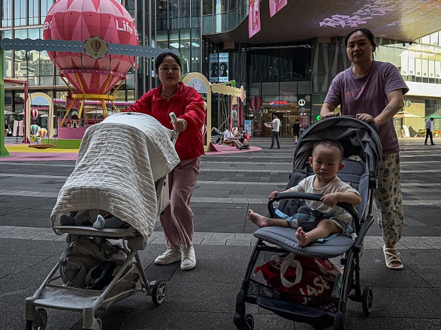 CHONGQING, CHINA - MAY 20: Women push strollers with young children through a commercial plaza featuring colorful decorations and play structures, including hot air balloon-themed displays, on May 20, 2025 in Chongqing, China. As concerns over declining birth rates persist, Chinese cities are increasingly investing in child-friendly infrastructure to encourage family-oriented lifestyles and support population growth initiatives. (Photo by Cheng Xin/Getty Images)