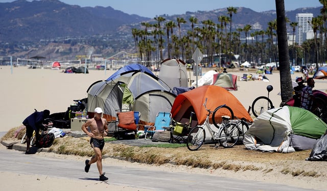 A jogger runs past a homeless encampment in the Venice Beach section of Los Angeles. (AP Photo/Marcio Jose Sanchez, File)