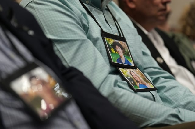 Friends and family of the 67 victims killed in a mid-air collision of a passenger jet and a US Army helicopter wear photographs around their neck during the National Transportation Safety Board investigation hearings
