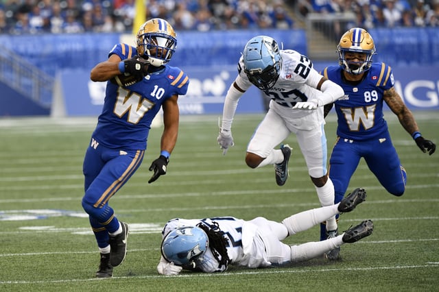 Winnipeg Blue Bombers' Nic Demski (10) carries the ball downfield after a catch past Toronto Argonauts' Mark Milton (27) and Benjie Franklin (23) during first half CFL action in Winnipeg, Friday, Aug. 1, 2025. THE CANADIAN PRESS/Fred Greenslade