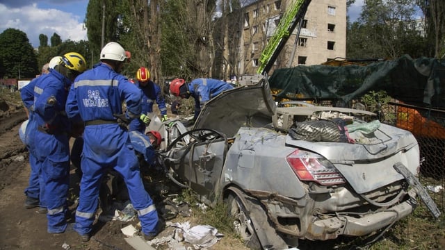 Emergency workers inspect a damaged car close to the multi-storey residential house that was ruined by a Russian missile Thursday night in Kyiv, Ukraine.