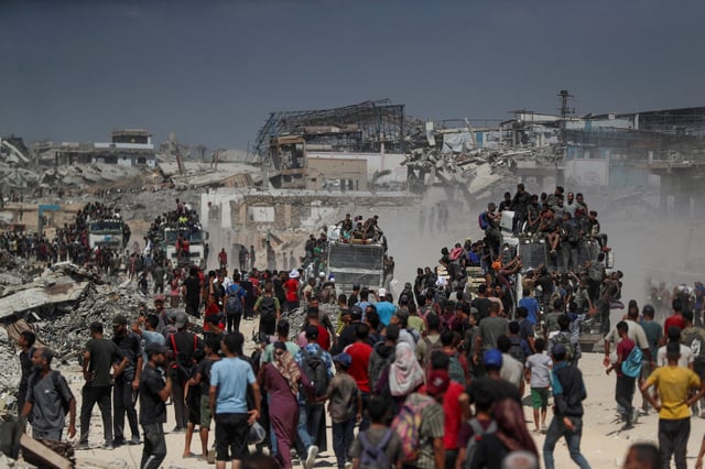 Palestinians climb onto trucks as they seek for aid supplies that entered Gaza through Israel in Beit Lahia, northern Gaza Strip, August 1, 2025. REUTERS/Mahmoud Issa/File Photo
