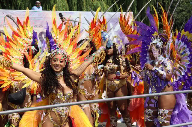 A masquerader in a fiery red and orange costume poses for the camera.