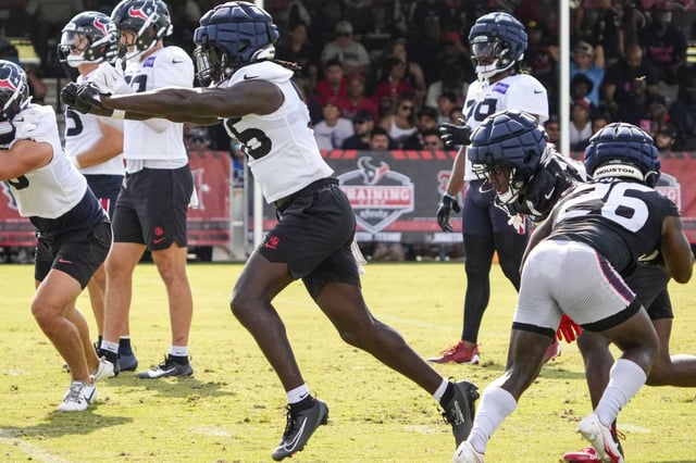 Houston Texans linebacker Jamal Hill (56) breaks through the line past running back J.J. Taylor (26) running special teams drills during an NFL training camp practice at Houston Methodist Training Center in Houston, Saturday, Aug. 2, 2025.