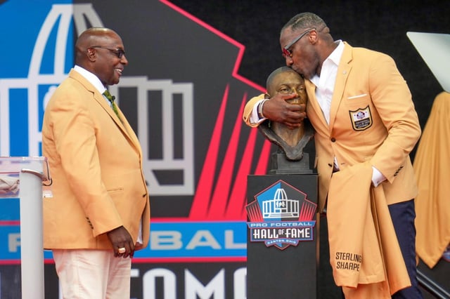 Former NFL player Sterling Sharpe, left, watches as his brother Shannon Sharpe kisses his bust during an induction ceremony at the Pro Football Hall of Fame on Saturday, Aug. 2, 2025, in Canton, Ohio. (AP Photo/Sue Ogrocki)