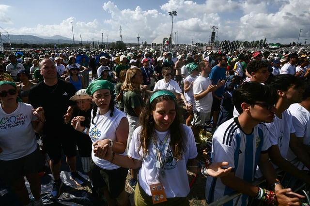 Young people hold hands during an open-air Mass in Rome as part of the Jubilee of Youth on August 3.