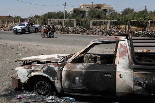 A Syrian security checkpoint is seen as forces deploy in Mazraa village on the outskirts of Sweida city, in southern Syria, Sunday, July 20, 2025. A burned-out vehicle is seen in the foreground. (AP Photo/Omar Sanadiki)