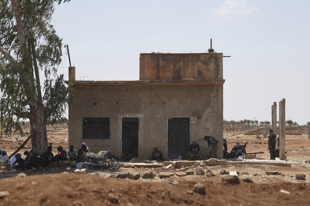 Bedouin fighters rest in the shade of a house as Syrian government security forces block them from entering Sweida province, in Busra al-Harir village, southern Syria, Sunday, July 20, 2025. (AP Photo/Ghaith Alsayed)