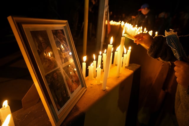 A person lights a candle during a vigil in front of El Teniente copper mine, operated by Codelco, where a cave-in killed one worker and trapped five others underground, halting operations in Rancagua, Chile, Saturday, Aug. 2, 2025. (AP Photo/Esteban Felix)