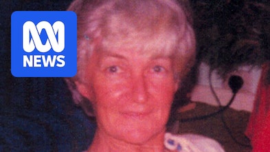 An old photograph of a middleaged woman with light blonde hair, a white blouse, smiling at the camera while sitting down.
