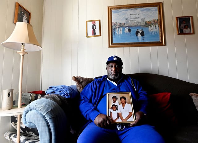 Bennie Clay sits on March 4, 2025, with a photo of his wife, Angela Clay, and their daughters, Latoya, 9, and Lakeisha, 6, who were killed in 1988 by Byron Lewis Black.