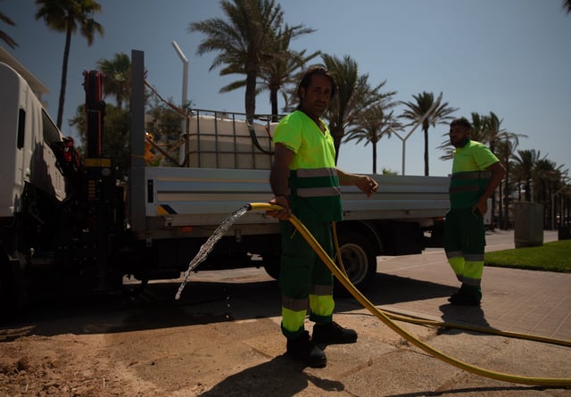 04 July 2025, Spain, Palma: A worker waters flower pots on the Arenal beach promenade on a warm summer's day. Photo: Clara Margais/dpa (Photo by Clara Margais/picture alliance via Getty Images)