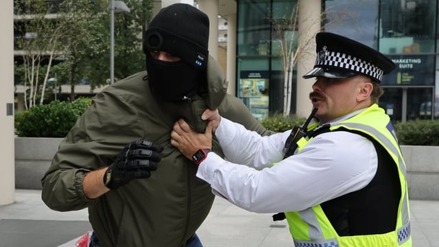 A masked protester outside the Britannia International Hotel in Canary Wharf on Sunday