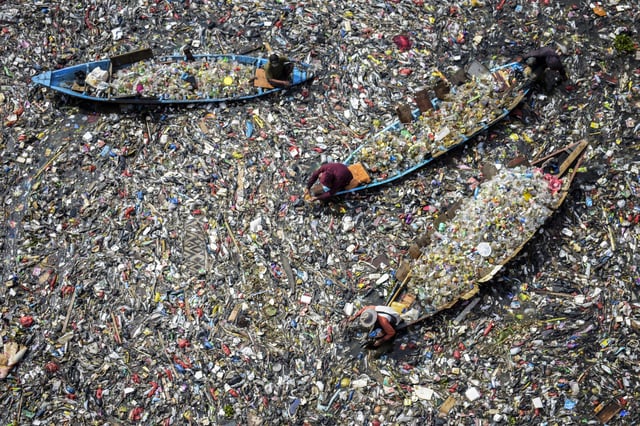 People on boats collect recyclable plastics from the heavily polluted Citarum River in Bandung, West Java, Indonesia, last June.