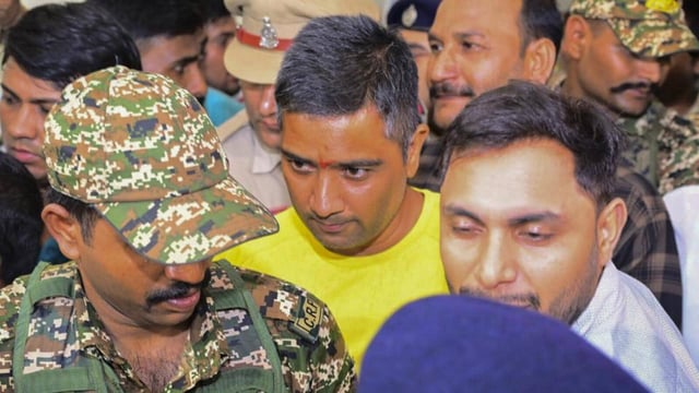 Security personnel and others escort Chaitanya Baghel (in yellow), the son of former Chhattisgarh CM Bhupesh Baghel, after his arrest by the Enforcement Directorate on July 18. (PTI)