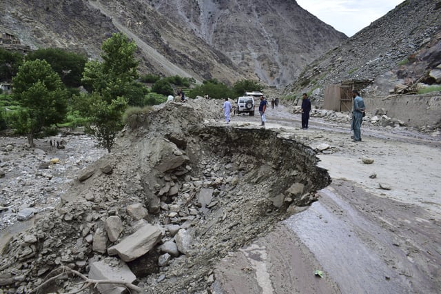Local residents walk on a damaged road following a cloudburst triggered landslide and flash flood on a highway near the Chilas district, northern Pakistan, Wednesday, July 23, 2025. (AP Photo/Saqib Manzoor)