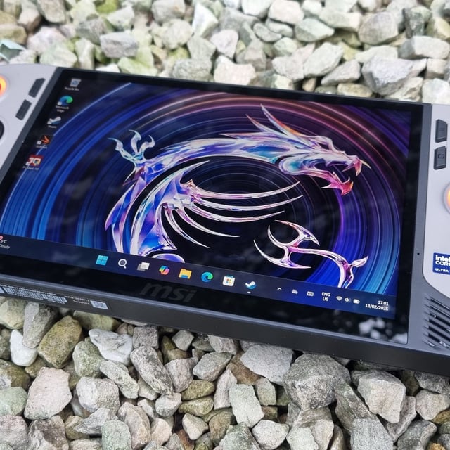 The MSI Claw 8 AI+ gaming handheld on some stones.