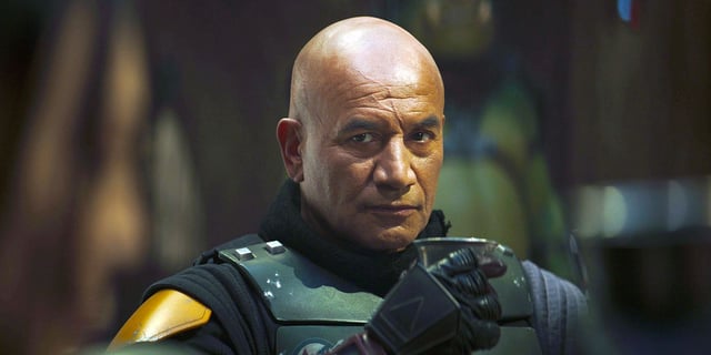 Boba Fett (Temuera Morrison) sits at a table and drinks in The Book of Boba Fett