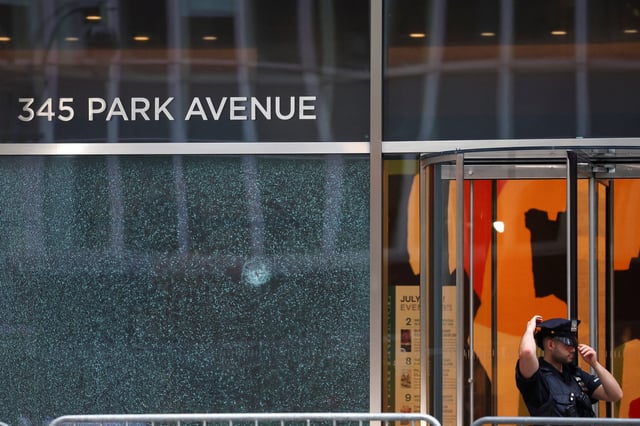 A police officer stands next to the glass window with a bullet hole near the scene of a deadly mass shooting in Manhattan, New York City, U.S. July 29, 2025. REUTERS/Mike Segar/File Photo
