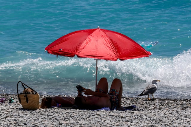 Des personnes se reposent sous un parasol sur la plage par une journée chaude et ensoleillée à Nice, France.