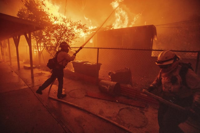 FILE - Firefighters protect a structure as the Eaton Fire advances Jan. 8, 2025, in Altadena, Calif. (AP Photo/Ethan Swope, File)