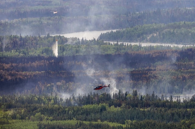 Helicopters crews work on a wildfire in northern Manitoba during a helicopter tour in the surrounding area of Manitoba, Canada, on June 12, 2025.